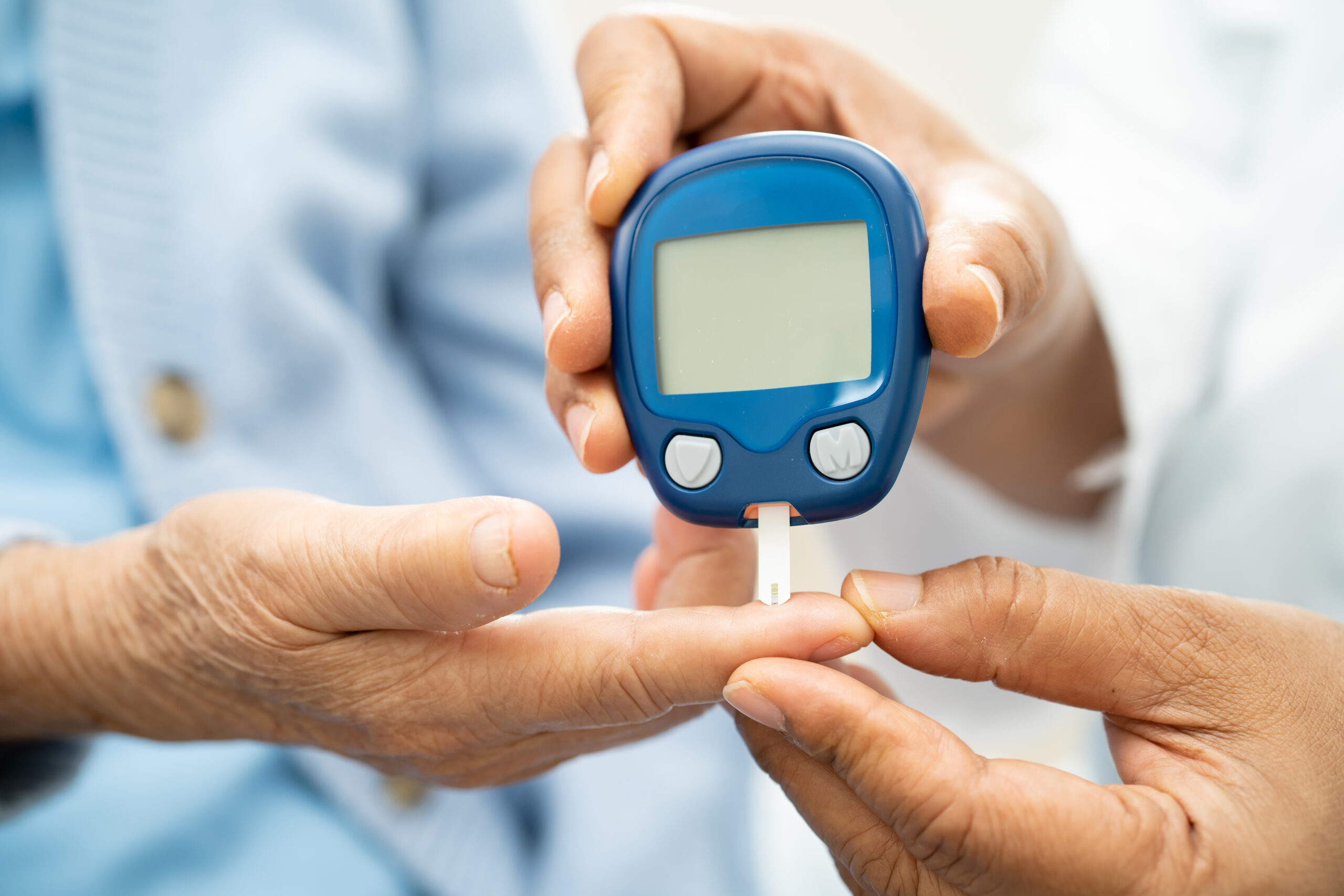 Doctor check diabetes from finger blood sugar level with finger lancet.