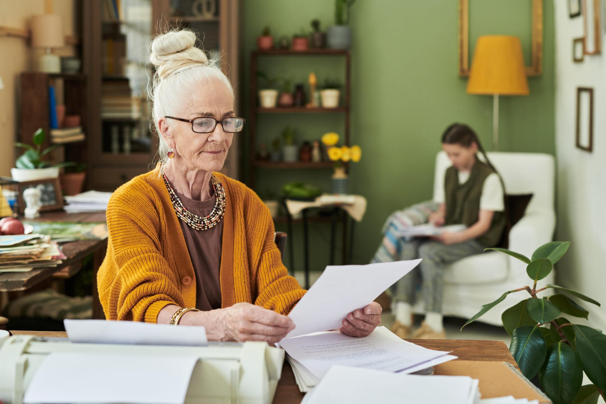 Elderly Woman Reviewing Papers at Home Desk