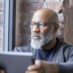 Portrait of pensive man with tablet looking out of window