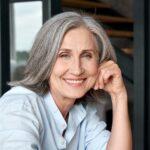 Smiling mature middle aged woman sitting at workplace, portrait.