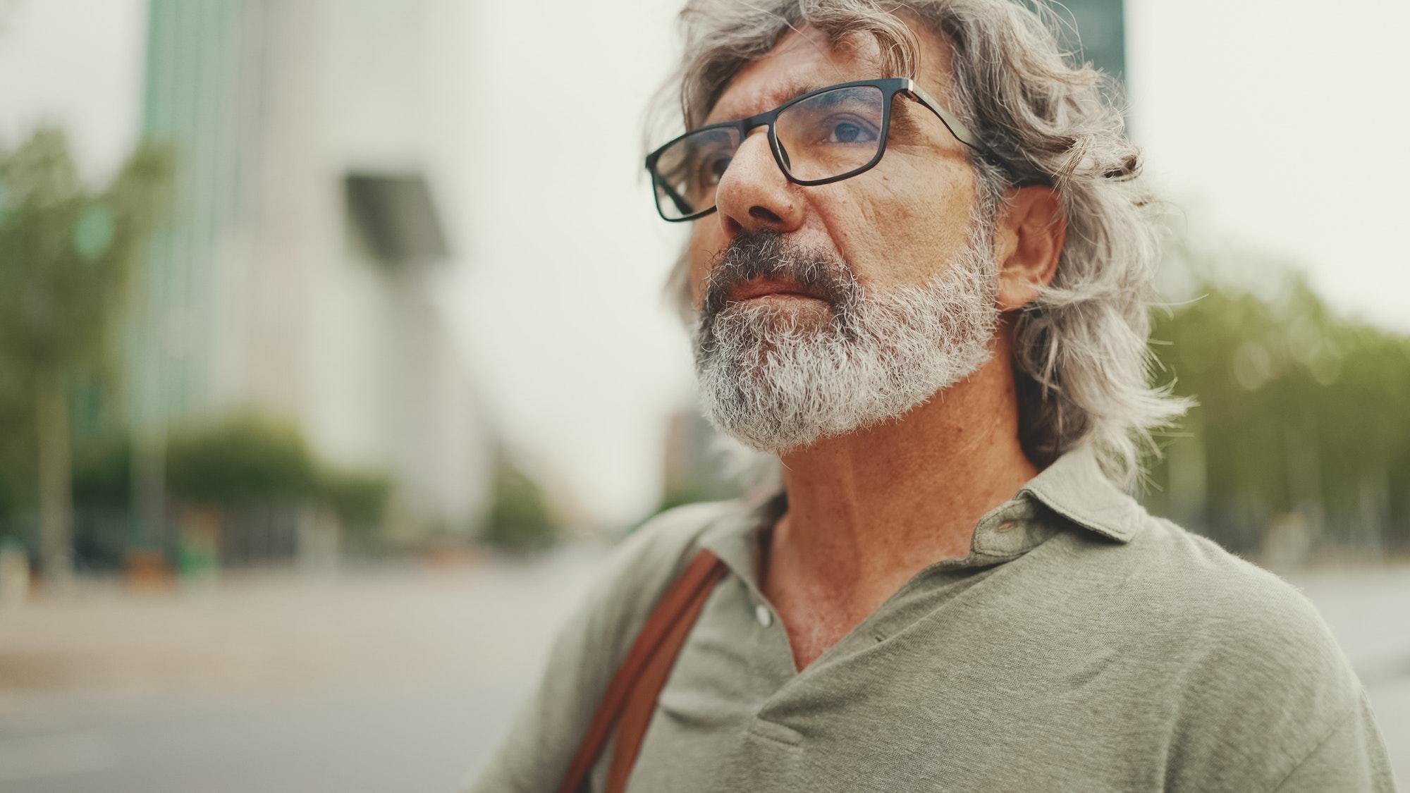 Clouse-up, friendly middle-aged man with gray hair and beard wearing casual clothes