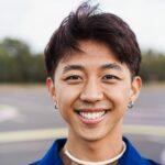 Happy gay chinese man with make-up smiling on camera outdoor - Focus on face