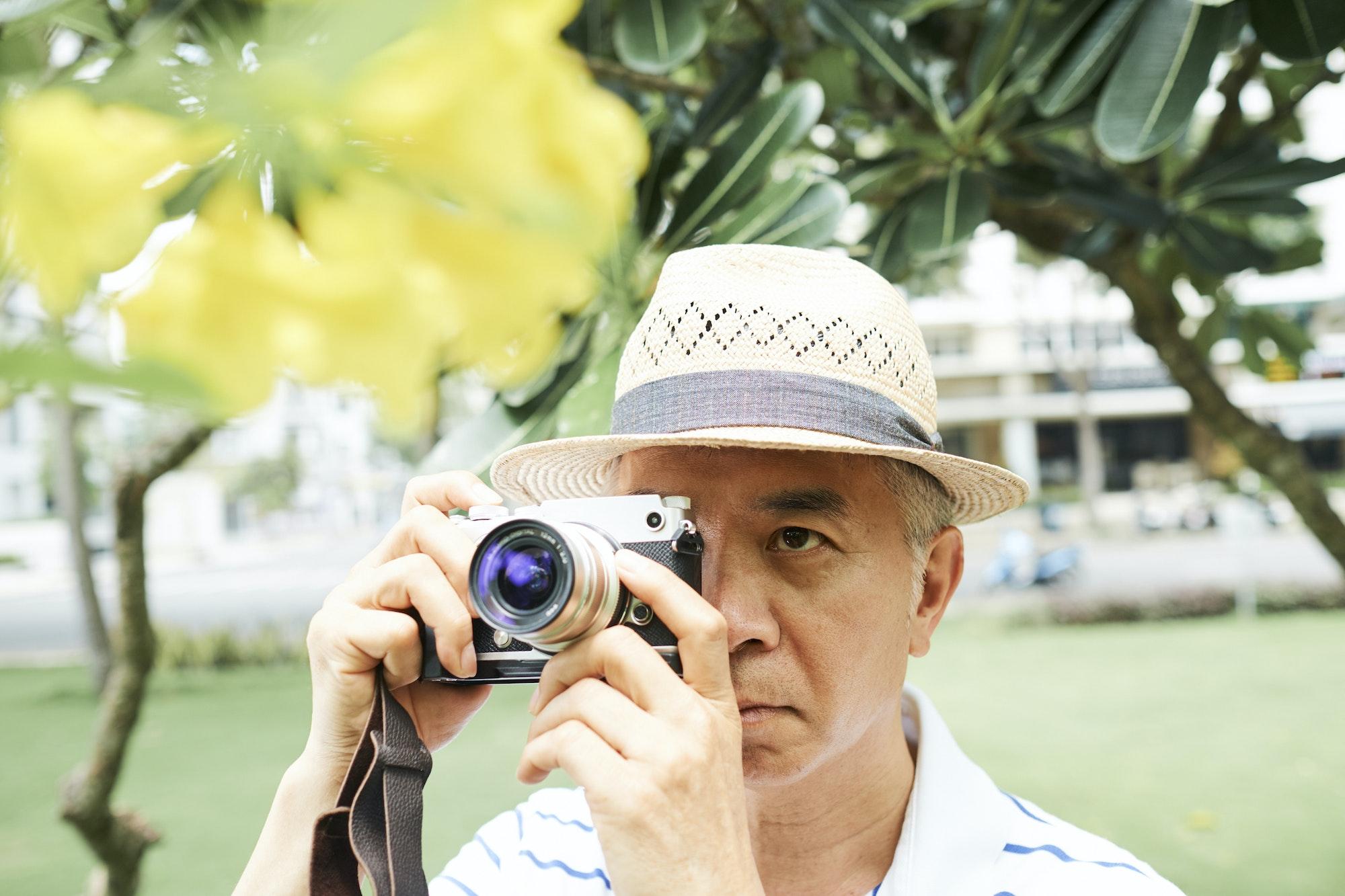 Senior Asian man photographig flower