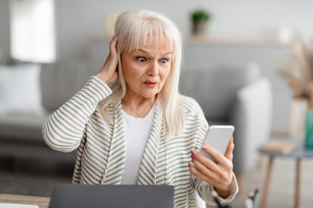 Shocked senior woman using her mobile phone