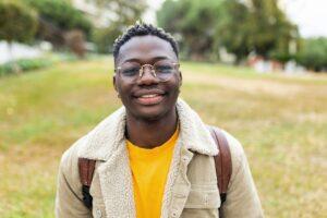 Smiling african young student man looking at camera outdoors