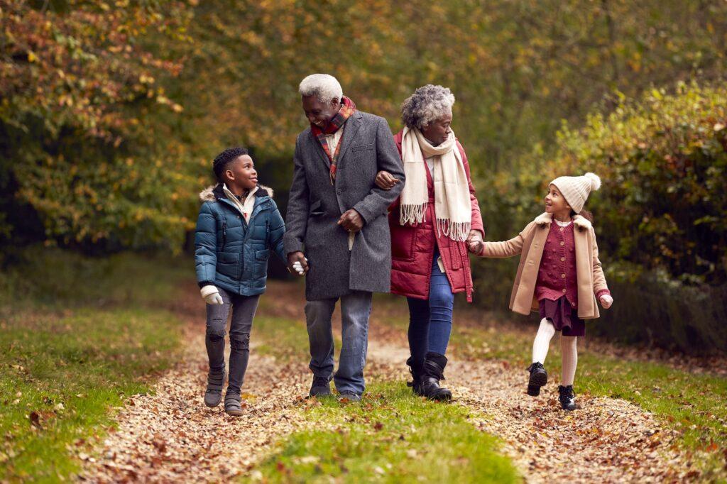 Grandparents Holding Hands With Grandchildren On Walk Through Autumn Countryside Together