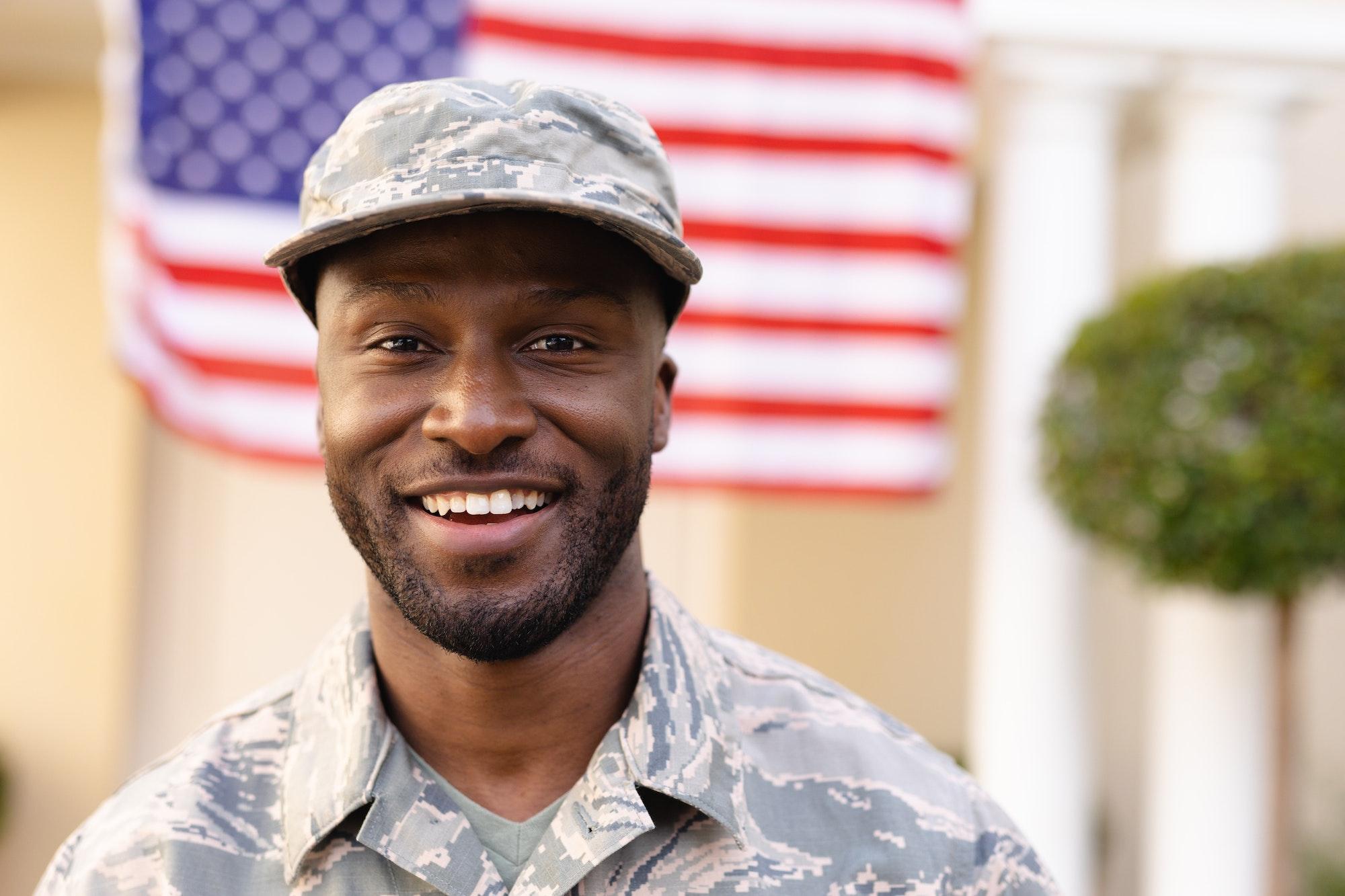 Portrait of smiling male african american soldier wearing camouflage uniform and cap