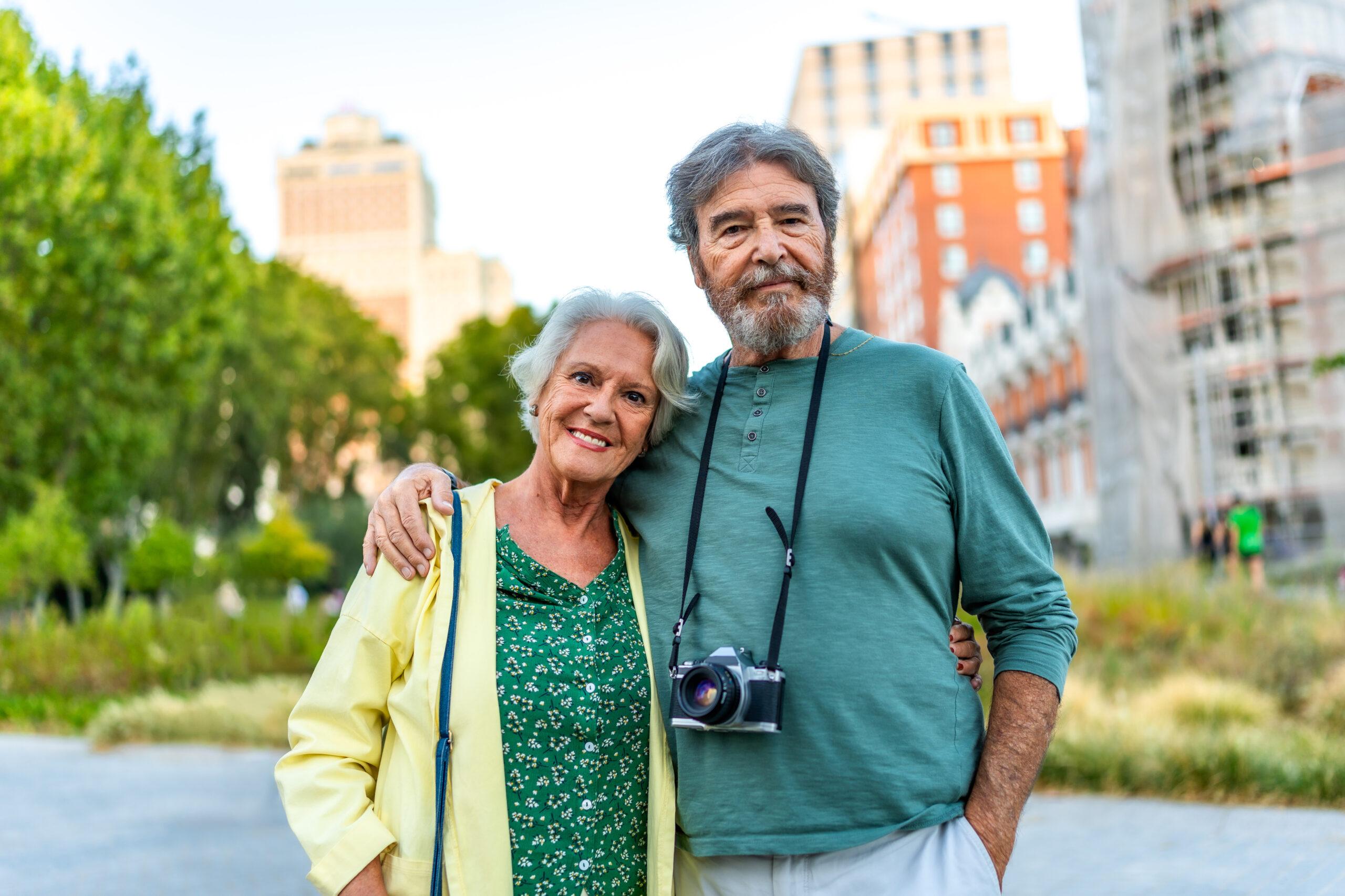 Portrait of senior couple of tourists standing embracing from shoulder in the city