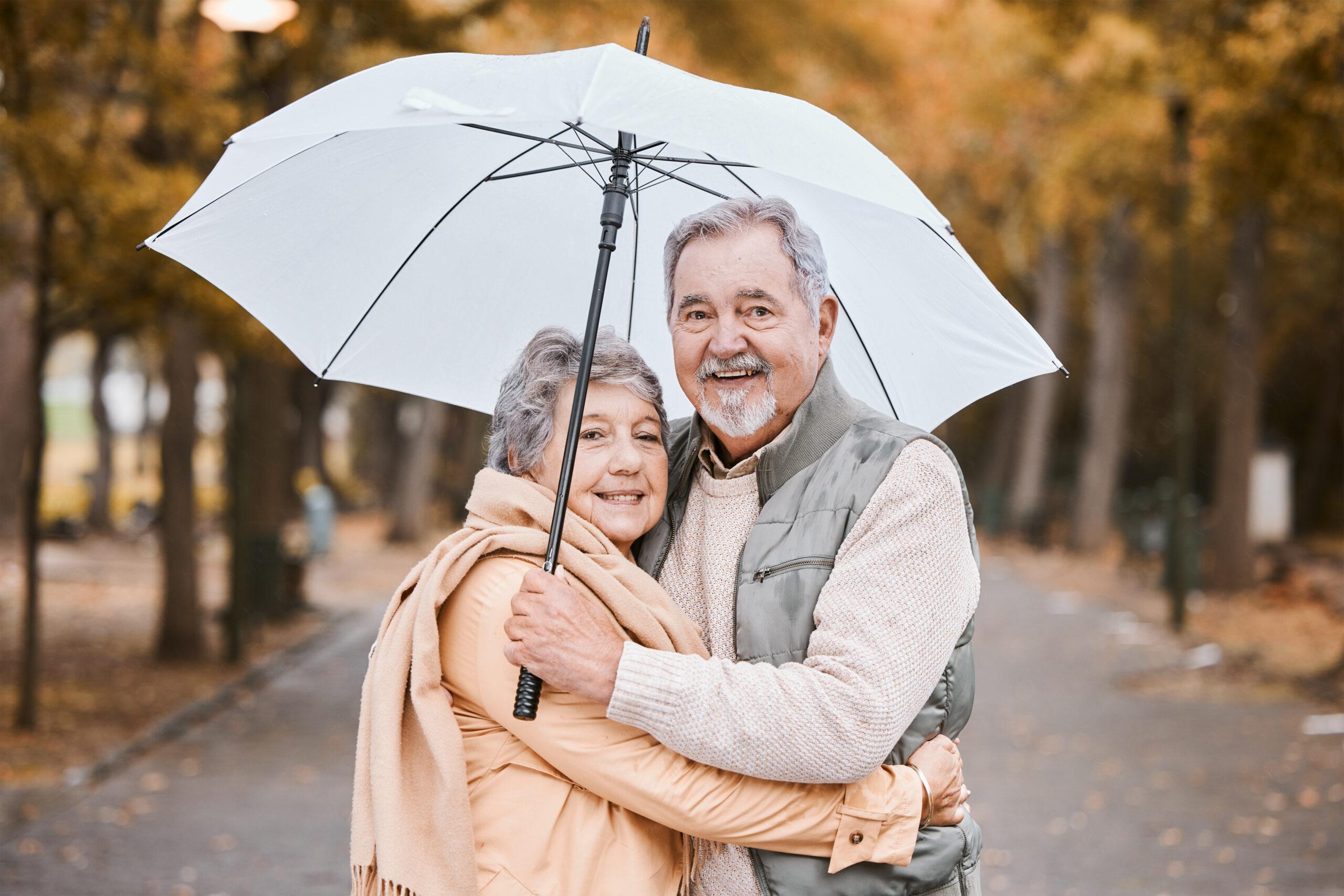 Winter, hug and senior couple in a park, retirement date and walking in Canada with an umbrella. Na.