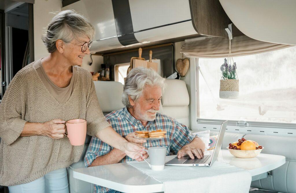Elderly couple in travel vacation inside a camper van enjoying breakfast together