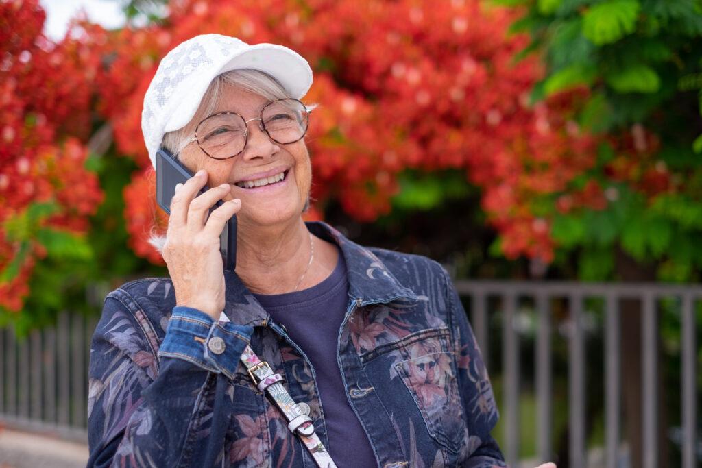 A woman wearing a white hat and jean jacket. She is talking on a cell phone.