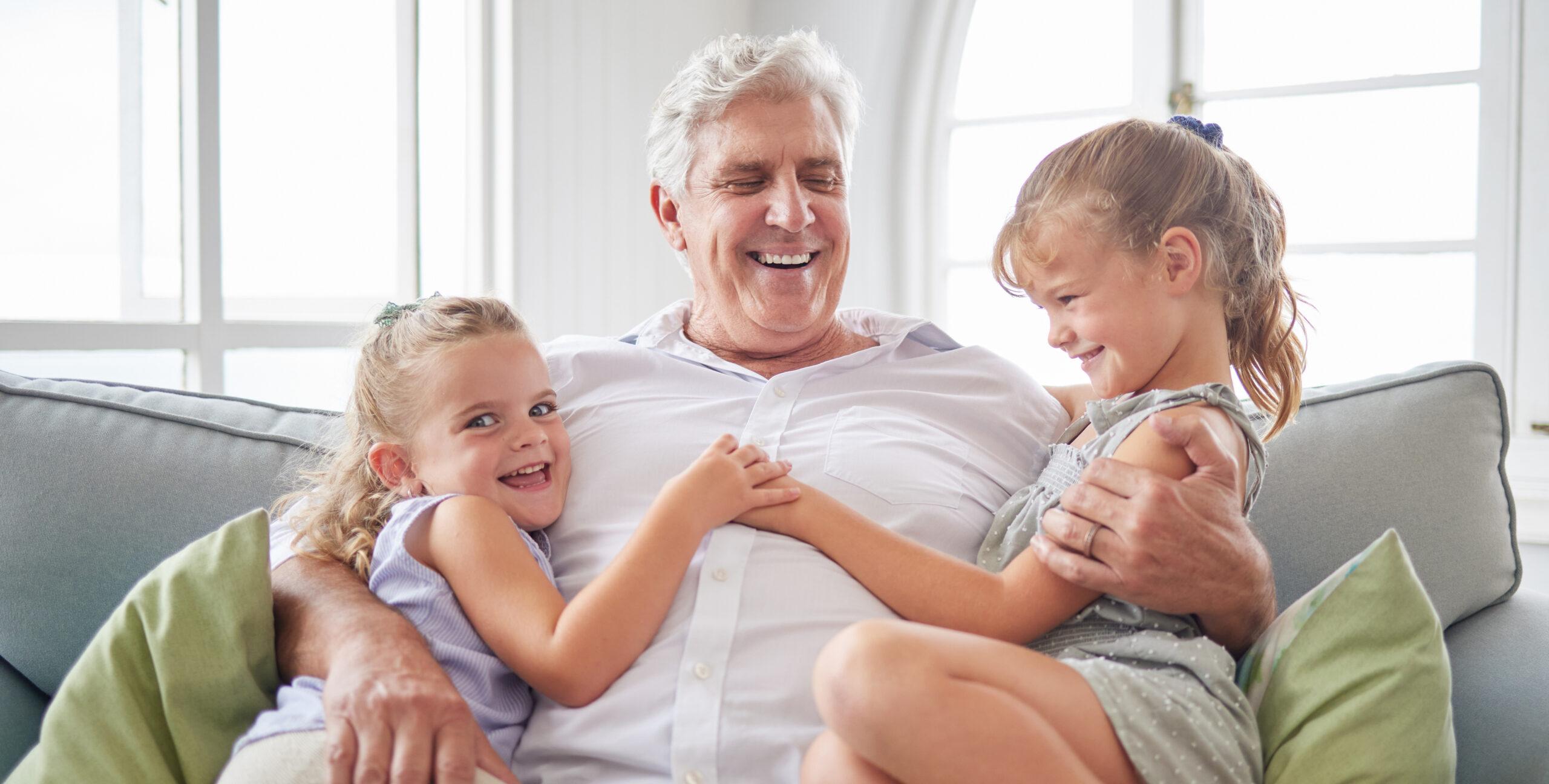 Grandfather with his grandchildren sitting on couch.