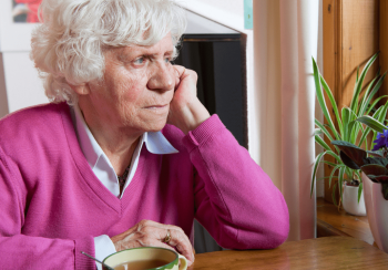 lady with tea looking out of window in pink sweater