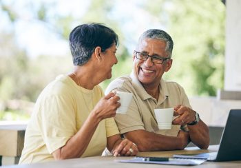 Couple having coffee and looking at laptop