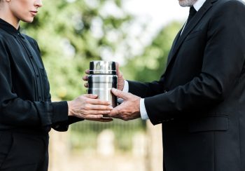 cropped view of senior man and woman holding mortuary urn