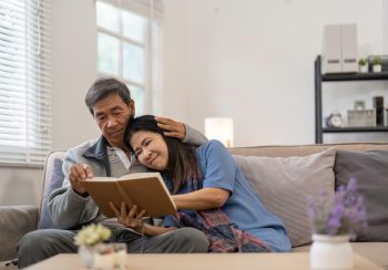 Elderly couple reading book together on couch, Concept of companionship and love