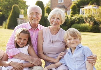 Grandparents and grandchildren sitting on grass in a garden