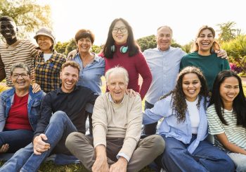 Group of multigenerational people smiling in front of camera - Multiracial friends of different ages having fun together - Main focus on asian center girl face