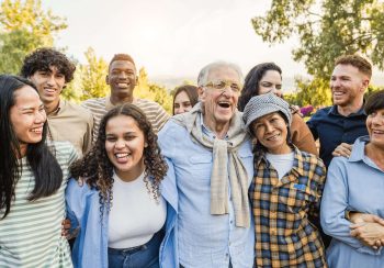 Group of multigenerational people smiling in front of camera - Multiracial friends of different ages having fun together - Main focus on caucasian senior face
