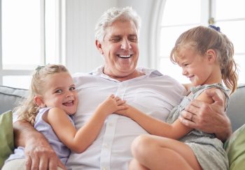 Grandfather with his grandchildren sitting on couch.