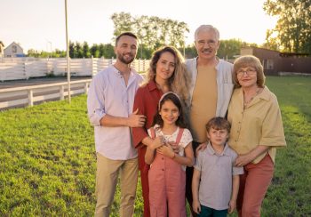 Large family of three generations standing on green lawn in the countryside