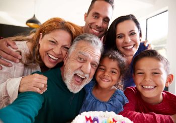 Multi-Generation Hispanic Family Taking Selfie To Celebrate Granddaughters Birthday At Home