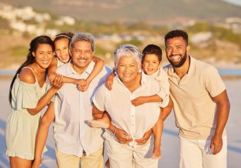 Portrait of a multi generation family on vacation standing together at the beach on a sunny day. Mi.