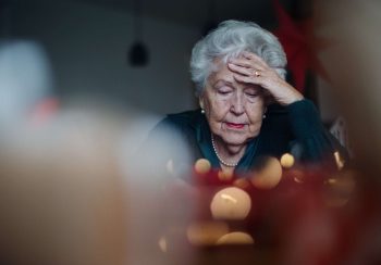 Unhappy senior woman sitting alone and crying during Christmas Eve. Concept of solitude seniors.